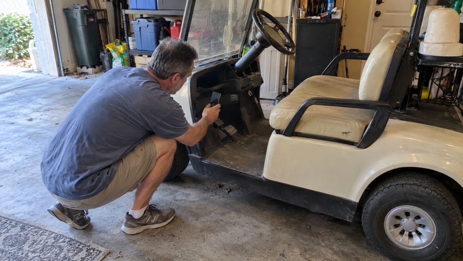 A homeowner casually photographs an identification plate beneath the dashboard of a used golf cart