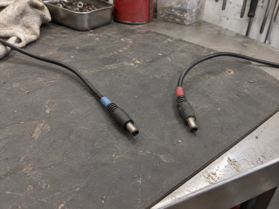 Two disconnected charger leads on a worn gray service mat