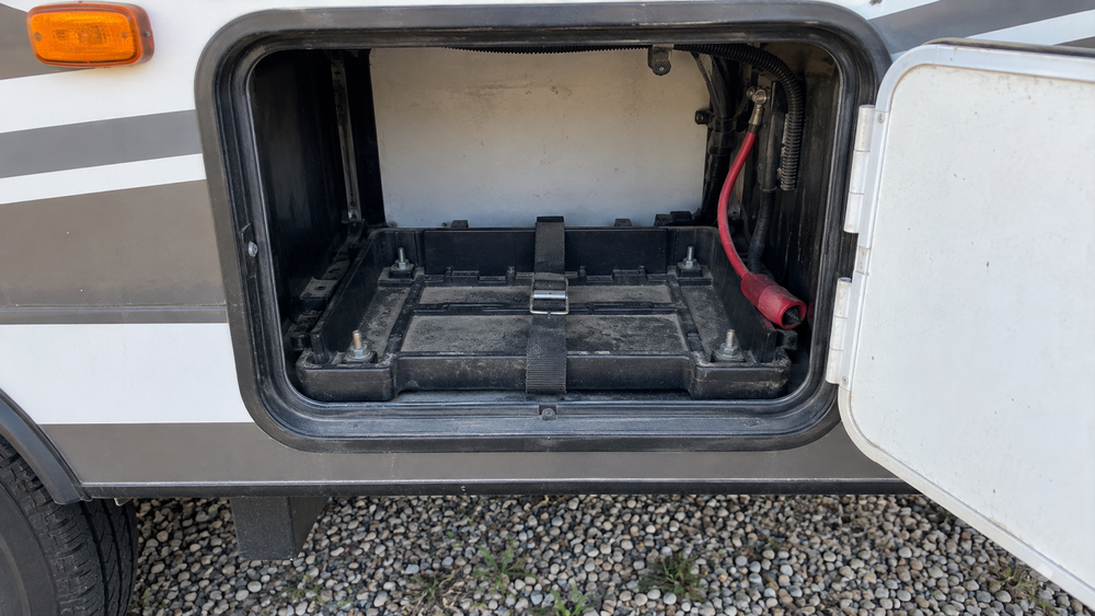 Open RV exterior compartment with an empty battery tray